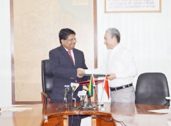 Finance Minister Dr Ashni Singh (left) and Chinese Ambassador to Guyana Zhang Limin exchanging documents.  (GINA photo) 