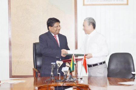 Finance Minister Dr Ashni Singh (left) and Chinese Ambassador to Guyana Zhang Limin exchanging documents.  (GINA photo)
