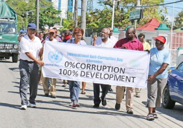 Members of TIGI’s Executive Body lead the way during yesterday’s march. Their banner demonstrates the theme of the occasion. (Photo by Arian Browne)