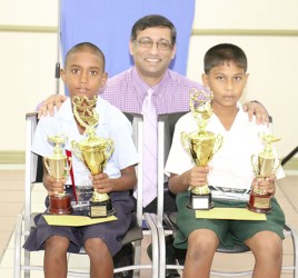 Runner-up Travis Williams of Sheet Anchor Primary School (left) and winner Daniel Premsukh of Mon Repos Primary (right) pose with their trophies after the conclusion of the GPL/IDB National Spelling Bee Competition. At centre is Aeshwar Deonarine, Deputy CEO of GPL.  