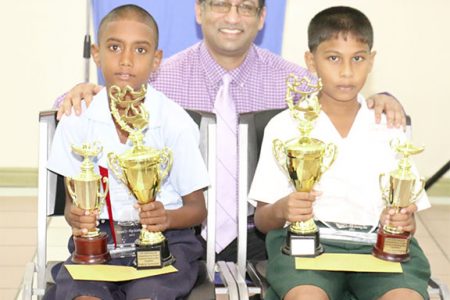 Runner-up Travis Williams of Sheet Anchor Primary School (left) and winner Daniel Premsukh of Mon Repos Primary (right) pose with their trophies after the conclusion of the GPL/IDB National Spelling Bee Competition. At centre is Aeshwar Deonarine, Deputy CEO of GPL.

