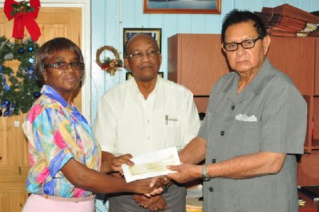 Assistant Public Relations Officer of Torginol Paints Inc, Sharon Blackman (left), hands over a sponsorship cheque for $282,000 to president of the Guyana Horse Racing Authority, Cecil Kennard at his office on Brickdam as Company Secretary, Percy Boyce Jr. looks on. (Orlando Charles photo)
