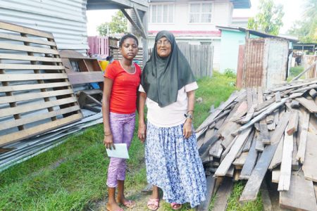 Farida Latiff and her daughter Rosanna stand near the materials from their dismantled home.
