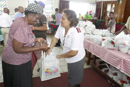 In the spirit of the upcoming season, at least 900 hampers were distributed yesterday by the Salvation Army to needy and senior persons of Guyana. The distribution is an annual fixture of the organization. Hampers will also be distributed in Berbice, Mahaicony, Bartica and other communities in Guyana. Salvation Army also plans on visiting the children’s ward of the Georgetown Public Hospital (GPH).  In photo, Major Laura Yangil-Augusto hands over a hamper to a recipient. (Arian Browne Photos)