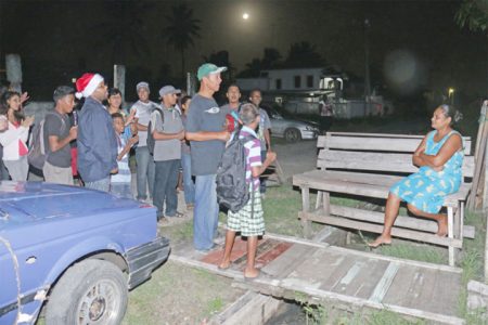 A Better Hope Assembly of God caroller singing ‘Hark the herald angels sing’ to a North Better Hope villager last evening. (Arian Browne photo) 