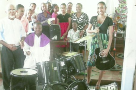 Members of the St Francis RC Youth Club try out the new drum set after the presentation while Father Joachim de Mello (standing left) looks on.