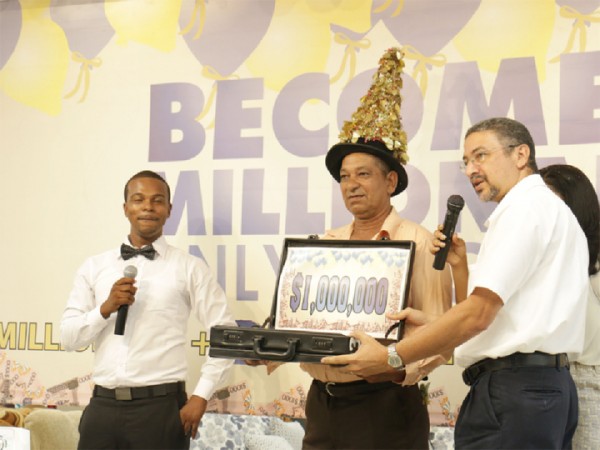  Rickey Isaacs (centre) of Berbice is the latest winner of the Courts Become a Millionaire promotion after he selected the right balloon yesterday at the Main Street store. At right is Managing Director at Courts, Clyde de Haas. At left is one of the hosts, DJ Akeelo. 