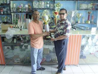 Proprietor of the Trophy Stall, Ramesh Sunich handing over the champion’s jockey trophy for the Kennard’s Memorial Turf Club (KMTC) Boxing Day meet for the 25th year to president of the Guyana Horse Racing Authority, Cecil Kennard. 