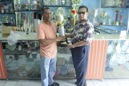 Proprietor of the Trophy Stall, Ramesh Sunich handing over the champion’s jockey trophy for the Kennard’s Memorial Turf Club (KMTC) Boxing Day meet for the 25th year to president of the Guyana Horse Racing Authority, Cecil Kennard.
