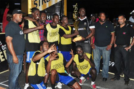 Guinness Brand Manager Lee Baptiste handing over the championship trophy to Queen Street Tiger Bay’s Captain Keoma Gravesande while members of the winning team, Banks DIH and the Petra Organization look on. (Orlando Charles photo)