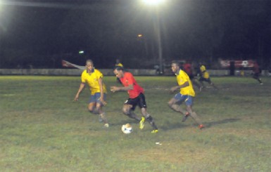 Alpha United Gregory Richardson on the attack with two Pele players in hot pursuit. (Orlando Charles photo) 