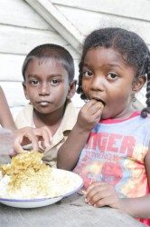 These two children were snapped eating a meal of fish curry.  