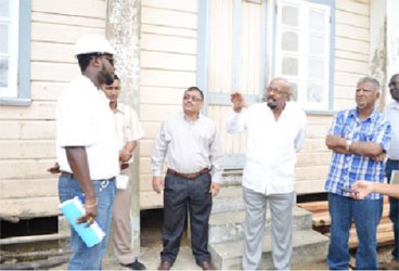 Minister in the Ministry of Local Government and Regional Development, Norman Whittaker (fourth from left), engaging Quacey Amsterdam, the contractor at the Novar Primary School, Region 5. (GINA photo) 