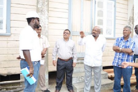 Minister in the Ministry of Local Government and Regional Development, Norman Whittaker (fourth from left), engaging Quacey Amsterdam, the contractor at the Novar Primary School, Region 5. (GINA photo)
