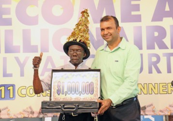Courts’ latest millionaire Kenneth Dey receiving his million dollar briefcase from Courts Finance Director Steve Nauth on Thursday after it was announced that he had chosen the balloon with the one million dollar jackpot.