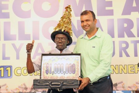 Courts’ latest millionaire Kenneth Dey receiving his million dollar briefcase from Courts Finance Director Steve Nauth on Thursday after it was announced that he had chosen the balloon with the one million dollar jackpot.