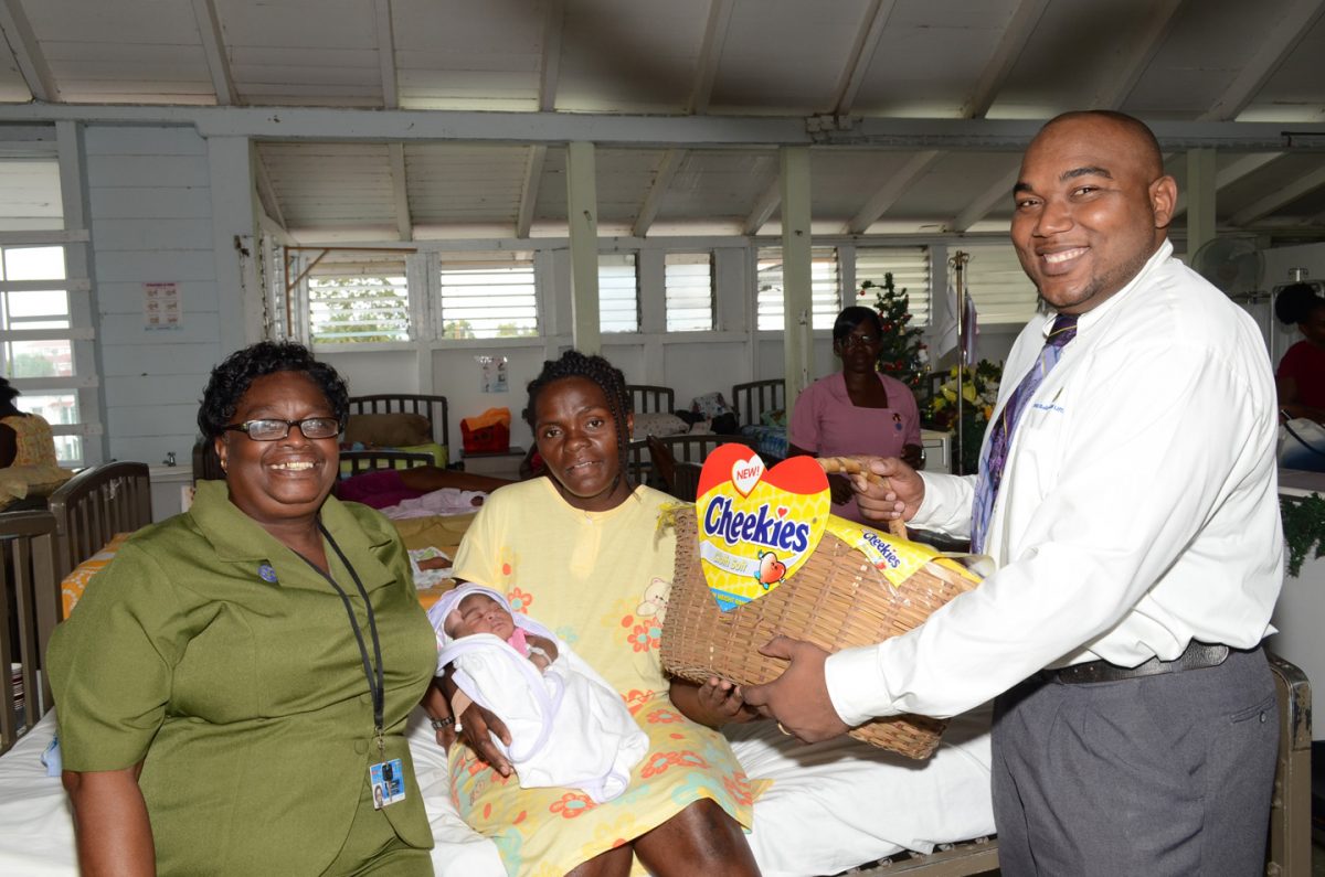 ANSA McAl handed out “Cheekies Bundles of Joy” to 15 mothers who delivered babies on Christmas Day at the Georgetown Hospital Public Hospital. Photo shows Ulanda Adams (centre) with her first daughter. Also in photo are ANSA Marketing Assistant Joel Lee (right) and sister Jennifer Cato. (ANSA McAl photo)