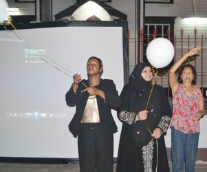 Minister of Human Services and Social Security Jennifer Webster (left), Chairperson of the Rights of the Child Commission Aleema Nasir (centre) and First Lady Deolatchmee Ramotar letting go of balloons in front of Parliament building last night, symbolising the lives of women that were lost due to domestic violence. (GINA photo)