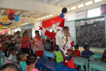 Yesterday,  First Lady Deolatchmee Ramotar’s  Foundation treated more than 240 children at a Christmas party held at the Charity Primary School, Region 2.  Photo shows Santa amid jollification. (Photo provided by First Lady’s office)