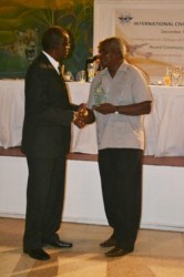 Former Guyana Airways pilot Rodwell Astil Paul (left) receiving his long service award from Minister of Transport Robeson Benn. (GINA photo)