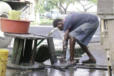 An Albouystown resident washes his feet after helping to clean the drains.  