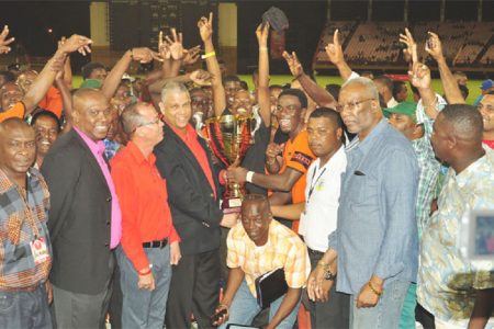 Slingerz FC captain Dwain Jacobs collecting the championship trophy from Banks DIH Limited Brand Executive Carlton João while members of the GFA, GFF, Banks DIH and Slingerz look on.
