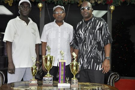 Secretary of the Georgetown Dominoes Association Mark Wiltshire (left), president of the USA Dominoes Federation George Abrams (centre) and PRO of the GDA Basil Bradshaw display the trophies.
