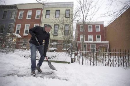 New York Mayor Bill de Blasio clears the snow from the sidewalk in front of his Brooklyn New York home.