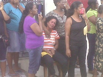 A distraught Jennifer Dyal (seated) Judith D’Oliviera’s sister, being comforted by residents as the body was being removed yesterday. 