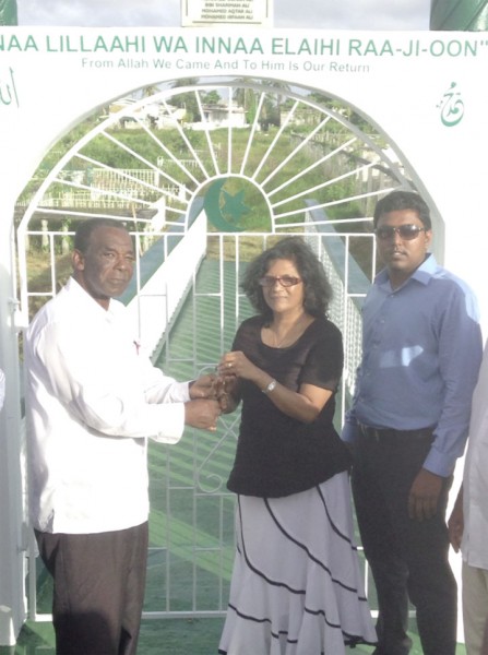 In the spirit of kindness, a local family donated a bridge to the Neighbourhood Democratic Council (NDC) of Beterverwagting-Triumph to provide entrance into a cemetery. The bridge, donated by Mohamed Usam Ali and his family, started being built in October 2013 and is valued at $840,000. Bibi Shariman Ali of the donating family said that any deed done for the dead is a good one. In photo, Bruce Adams (left) Chairman of the Beterverwagting-Triumph NDC receives the key to the entrance of the cemetery from Bibi Shariman Ali. Looking on is another member of the Ali family. 
