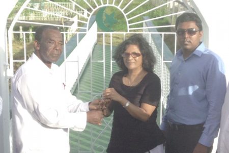 In the spirit of kindness, a local family donated a bridge to the Neighbourhood Democratic Council (NDC) of Beterverwagting-Triumph to provide entrance into a cemetery. The bridge, donated by Mohamed Usam Ali and his family, started being built in October 2013 and is valued at $840,000. Bibi Shariman Ali of the donating family said that any deed done for the dead is a good one. In photo, Bruce Adams (left) Chairman of the Beterverwagting-Triumph NDC receives the key to the entrance of the cemetery from Bibi Shariman Ali. Looking on is another member of the Ali family. 
