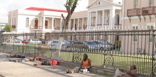 Staking their places early: Vagrants took up their sleeping positions outside Parliament early yesterday afternoon. Speaker of the National Assembly Raphael Trotman has said he may not work this Thursday but instead lead a protest to press authorities to clean the area, which apart from vagrants is bordered by stagnant drains and garbage. (Photo by Arian Browne)