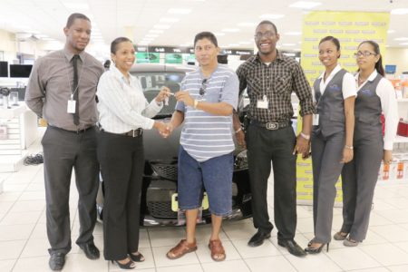 Enmore villager Francis Koo (third from left) as he receives the key to his new Mazda Demio car from Marketing Director of Courts Molly Rampersaud. With them are some of Courts’ marketing staff. 