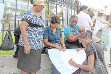 Protestors writing more placards as other people began to join the demonstration. (Photo by Arian Browne)