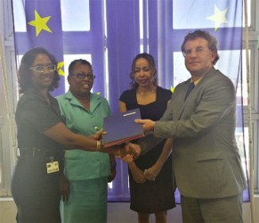 Ambassador Robert Kopecký [right] hands over the agreement to Omattie Madray of ChildLink [left] Director of Forward Guyana Chantalle Haynes [second, right] and Head of the Child Care and Protection Agency Ann Greene [second, left] look on. 