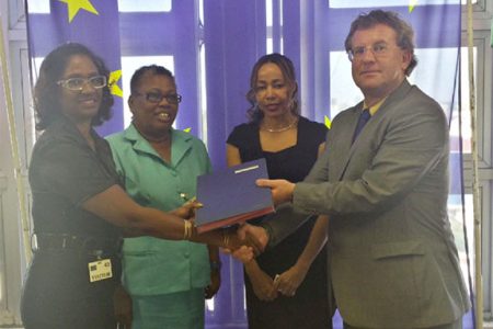 Ambassador Robert Kopecký [right] hands over the agreement to Omattie Madray of ChildLink [left] Director of Forward Guyana Chantalle Haynes [second, right] and Head of the Child Care and Protection Agency Ann Greene [second, left] look on. 