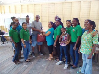 The Rotary Club of Demerara presents a donation of clothing to the head teacher at the school in Malali during a medical outreach, while Rotarians and Rotaractors look on.  
