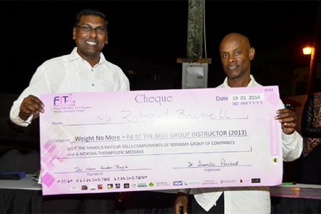  Best Group Instructor Robert Brumell (right) as he received his cheque from Chief Medical Officer Shamdeo Persaud