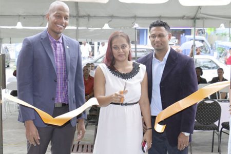 Subrina Sukhu (centre) cuts the ribbon, opening the new Digital Technology store on Brickdam. She is flanked by President of Georgetown Chamber of Commerce and Industry Clinton Urling (left) and her husband.
