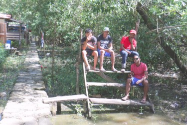 A group of young boys hanging out along the concrete walkway leading out to the river. The  pathway leads to a stone structure which the residents call the ‘First Baby monument’ at the end of the squatting area.  