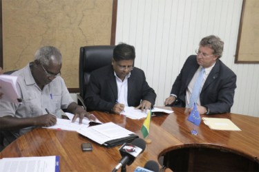 Works Minister Robeson Benn (left) and Finance Minister Dr Ashni Singh (centre) sign the agreement while EU Ambassador Robert Kopecký looks on. (Arian Browne photo) 