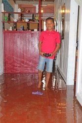 A boy stands in a flooded home along Cemetery Road