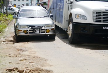 A vehicle trying to manoeuvre on the deplorable street where a truck is parked