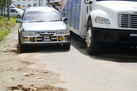 A vehicle trying to manoeuvre on the deplorable street where a truck is parked