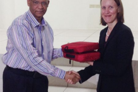 Minister of Home Affairs Clement Rohee (left) receives two of the 200 fraudulent document detection kits from Canadian High Commissioner Nicole Giles (right).
