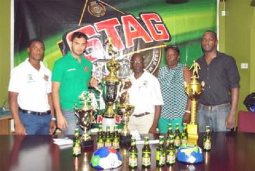 General Manager of the Slingerz FC, Colin ‘BL’ Aaron and Brand Manager of Stag, John Maikoo pose for a photo opportunity with the champion’s trophy following the launch of yesterday’s second annual West Side Stag/Mashramani Champion’s Cup. Looking on are (from left), Vurlon Mills, Christine Schmidt and Rawle Toney. (Orlando Charles photo)