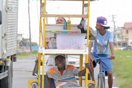 This young man was captured taking a shady ride on his friend’s food cart along the West Coast Demerara road at Uitvlugt. (Photo by Arian Browne)