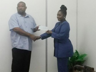 Dionne Johnson, Sales Supervisor of Mohammed’s Enterprise, hands over the sponsorshgip cheque to Hilbert Foster of the Rose Hall Town Youth and Sports Club.