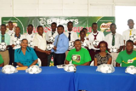 Beepat’s Treion D’Anjou presents a game ball to a student of St. George’s High School, the defending champions during yesterday’s briefing with coaches and captains of the Milo U-20 school tournament. (Orlando Charles photo)