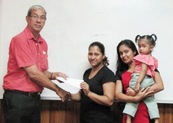 Proprietor of DeSinco Trading, Frank DeAbreu (left) hands over the cheque to mother of the child Sandra Seepersaud (DeSinco photo)